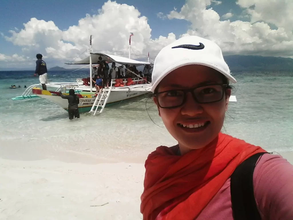 selfie in Digyo Island white sand with a boat at the back 