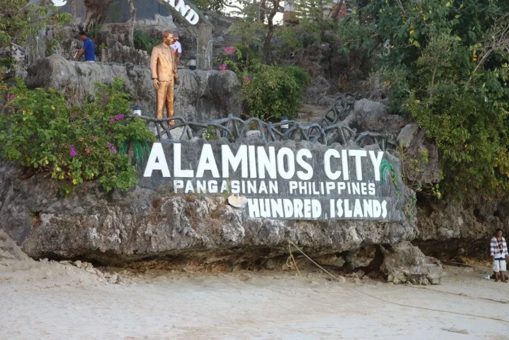 a rock with a word ALAMINOS CITY with a statue